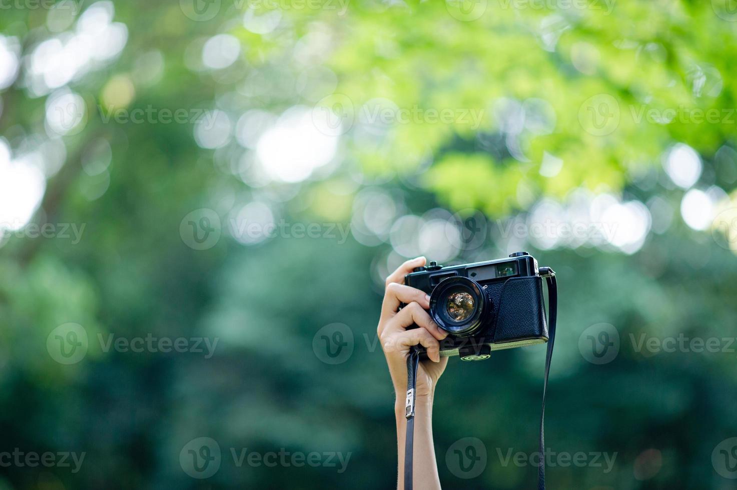 Fotograf und Kameraliebhaber schwarze Kamera und natürlicher grüner Hintergrund foto