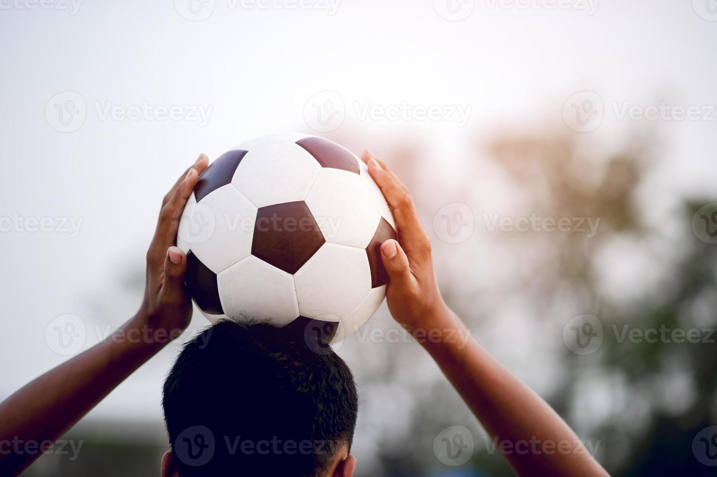 das zugeschnittene Bild von Sportlern, die den Ball und das Fußballfeld fangen. Sport-Image-Konzept. foto