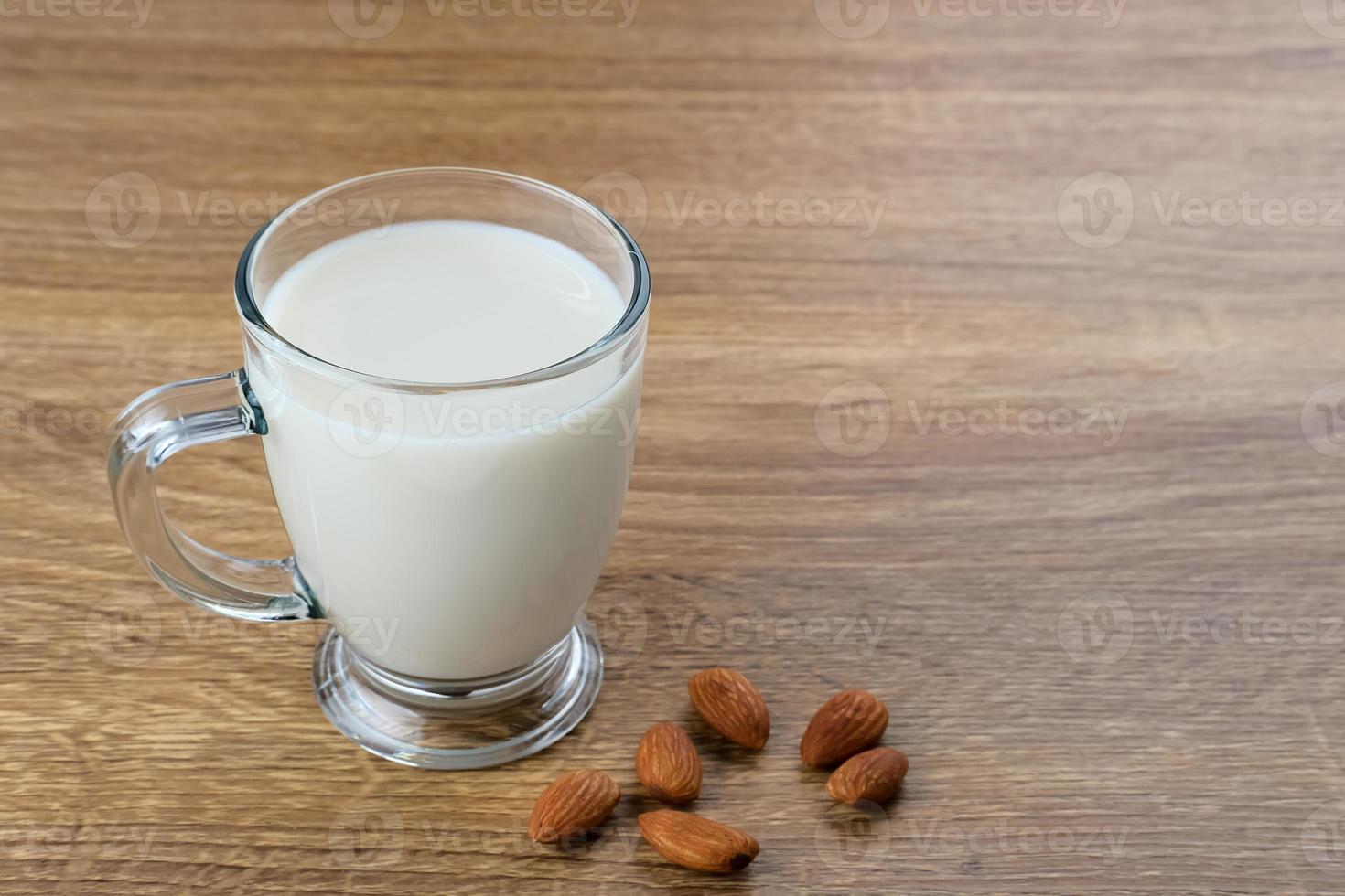 Mandelmilch im Glas mit Mandeln auf Holztisch. Platz für Text foto