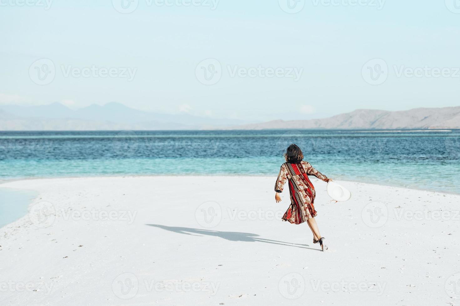 glückliche Frau läuft und tanzt am weißen Sandstrand foto