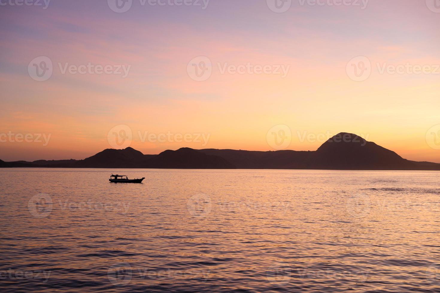 schwarze Silhouette von Hügeln mit traditionellem Fischerboot, das auf dem Meer bei labuan bajo segelt foto