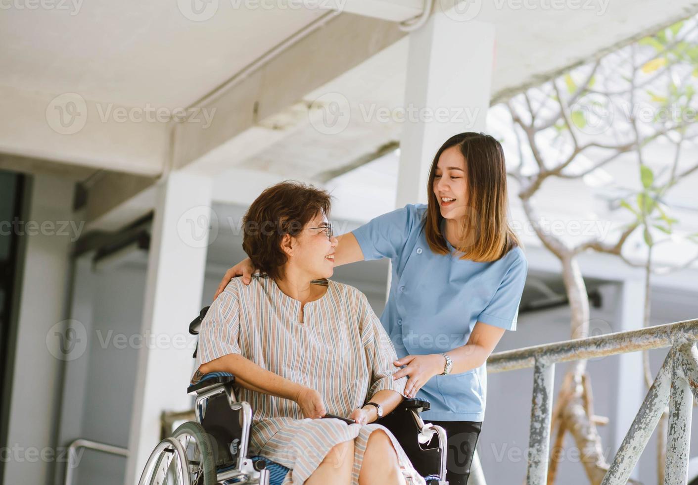 lächelnder Physiotherapeut, der sich um den glücklichen älteren Patienten im Rollstuhl kümmert foto