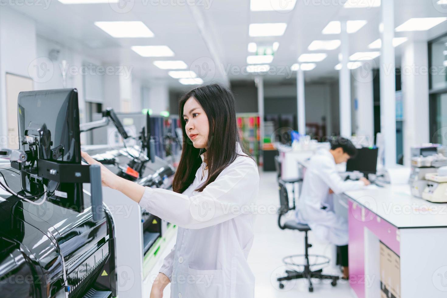 junge wissenschaftlerin, die mit einem automatisierten blutanalysatorbericht im medizinischen labor arbeitet foto