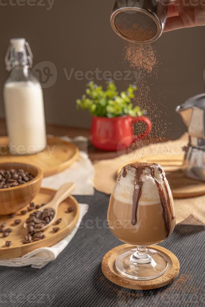 Mokka-Eiskaffee serviert mit Schlagsahne und Schokoladensirup in Weinglas auf Holztisch foto