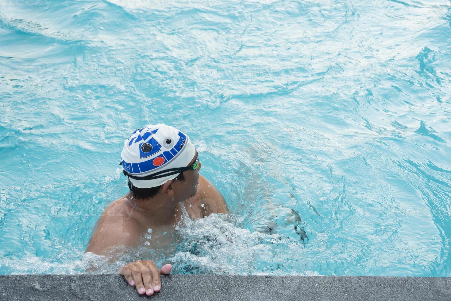 sportmann schwimmer in der kappe atmend ruhend müde beim trainingsschwimmen. Schwimmer im Pool. sportschwimmkonzept. foto