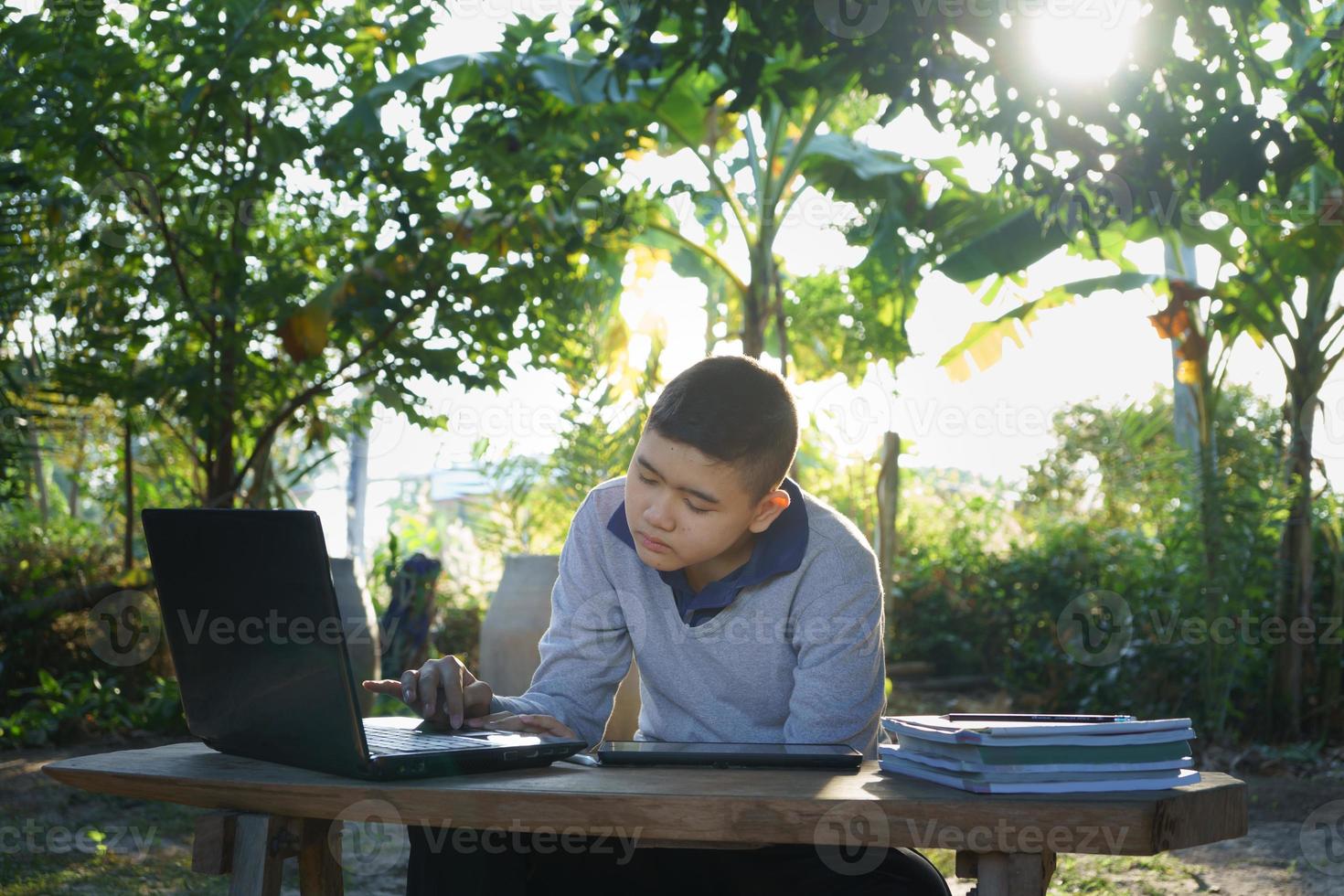 junge lernt online auf einem holztisch mit einem laptop und einem tablet in den morgenstunden in einem ländlichen haus. Konzept Online-Bildung auf dem Land und Arbeit von zu Hause aus foto