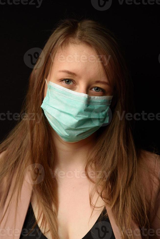 junges Mädchen in einer medizinischen Maske auf schwarzem Hintergrund. foto