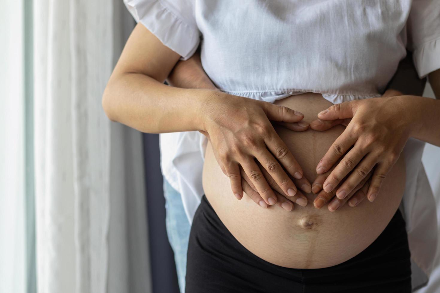 Smooth Focus, eine schwangere Frau und ihr Freund legen ihre Hände auf die Gebärmutter, um ihre Liebe für das ungeborene Kind zu zeigen. Liebeskonzept einer schwangeren Frau und ihres Geliebten gegenüber dem ungeborenen Kind. foto