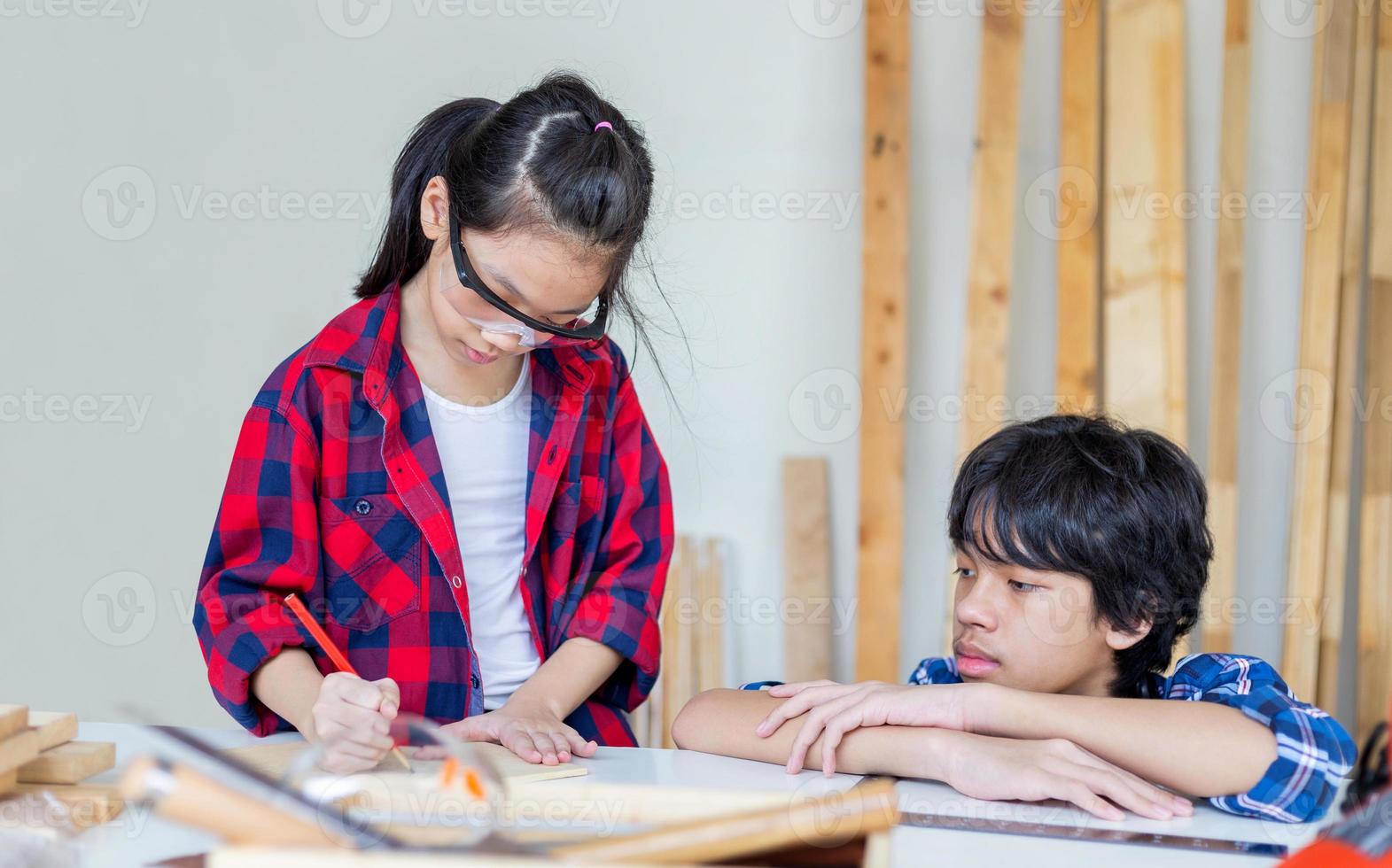 Kinder lernen Holzbearbeitung in der Handwerkswerkstatt, Teenagerjunge mit seiner kleinen Schwester bauen gemeinsam eine Werkstatt in einer Tischlerei. foto