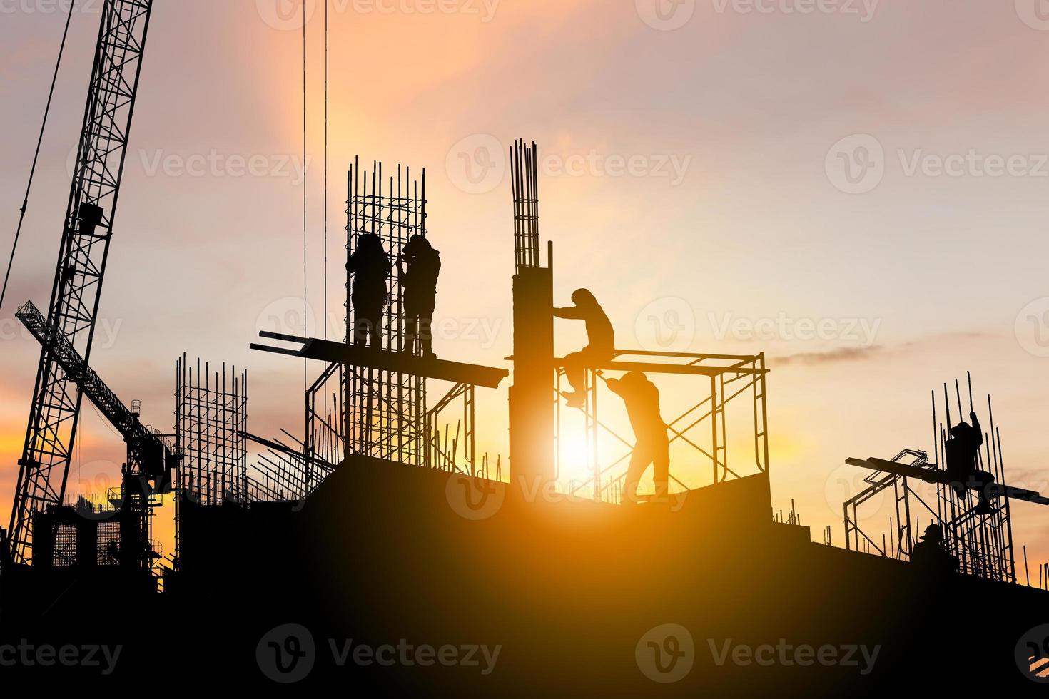 Silhouette des Arbeiterteams auf der Baustelle, Baustelle bei Sonnenuntergang am Abend foto