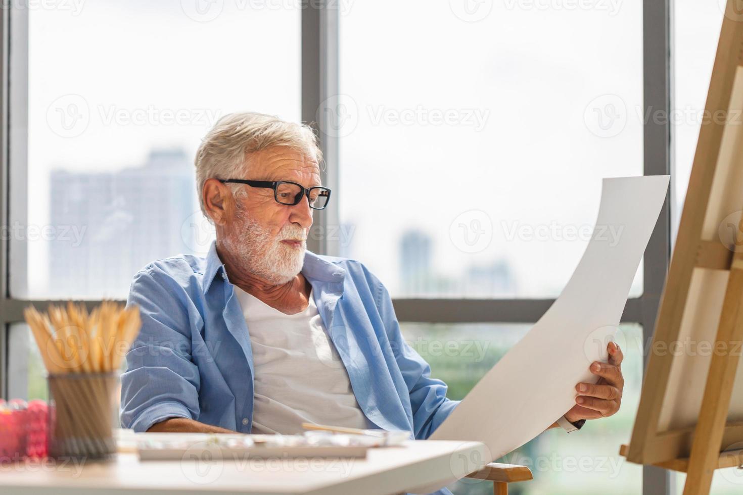 älterer mann, der auf einer leinwand malt, älterer maler, der ein gemälde betrachtet, glückliche ruhestandskonzepte foto
