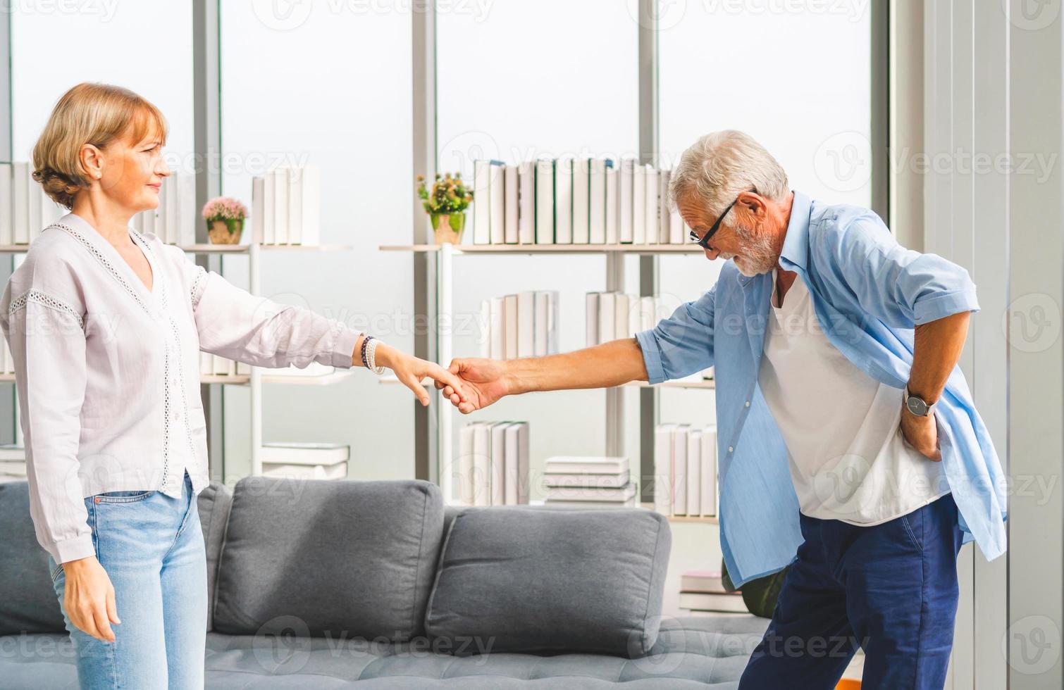 Porträt eines glücklichen älteren Paares, das im Wohnzimmer tanzt, einer älteren Frau und einem Mann, der tanzt, glückliche Familienkonzepte foto