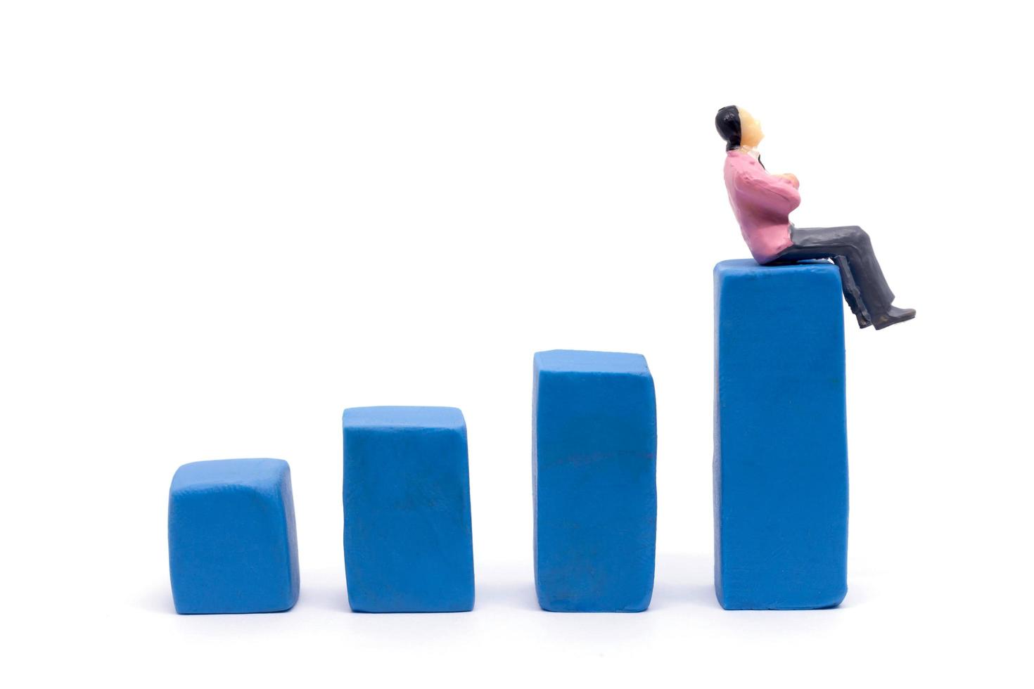 Miniaturgeschäftsmann und Diagramm auf weißem Hintergrund, Unternehmenswachstumskonzept foto