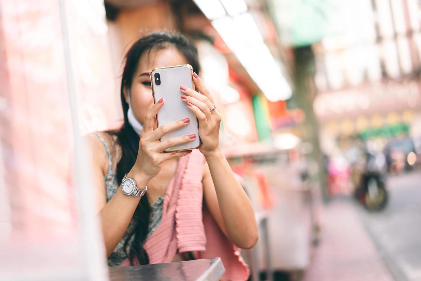 neue asiatische frau des normalen lebensstils, die intelligentes telefon verwendet. im Freien foto