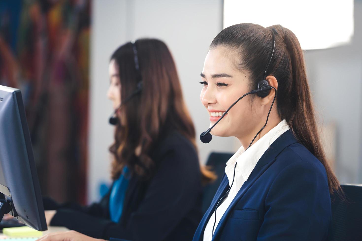 positives Lächeln junge asiatische Frau des Geschäftspersonals, die Kopfhörer und Computer verwendet. foto