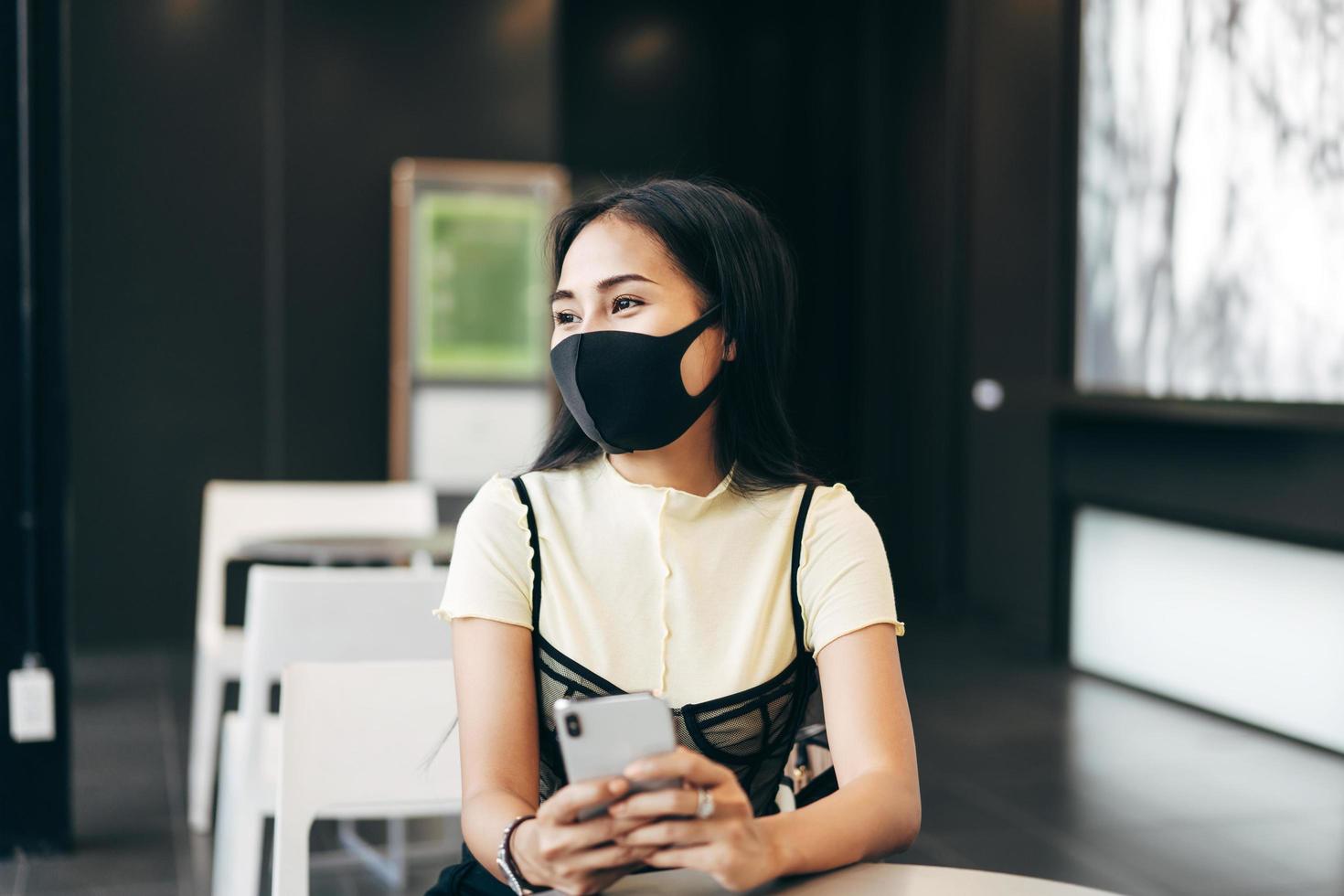 geschäftsfrau trägt eine schützende gesichtsmaske mit dem handy für online-dating foto