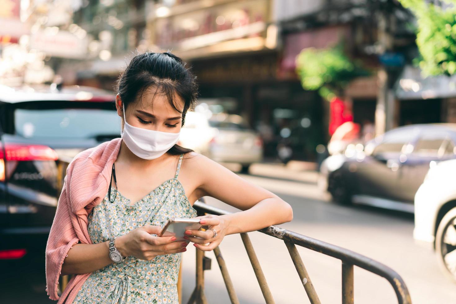asiatische erwachsene frau tan haut tragen maske auf gesicht und mit smartphone. foto