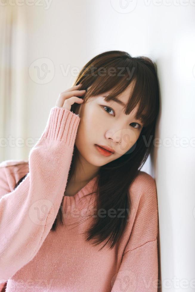 porträt junge asiatische nette frau jugendlich magere wandabnutzung rosa pullover. foto