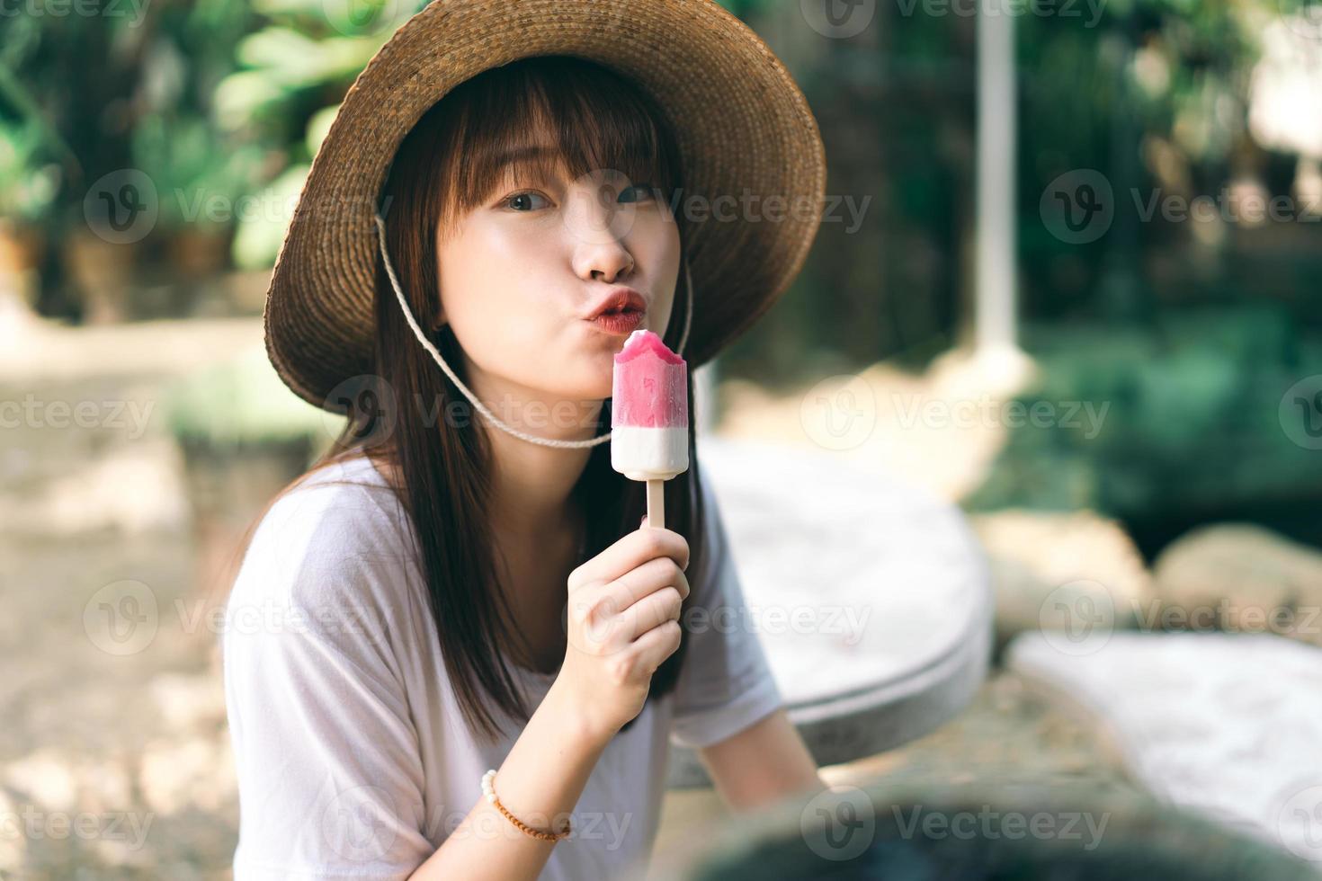 asiatische Teenager-Frau, die Eis im Garten im Freien isst. foto