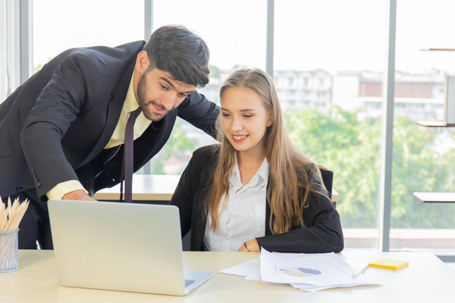 Zwei junge Geschäftsleute, Männer und Frauen, arbeiten im Büro mit einem Tablet und Begleitdokumenten auf dem Schreibtisch mit einem Lächeln und Glück. foto