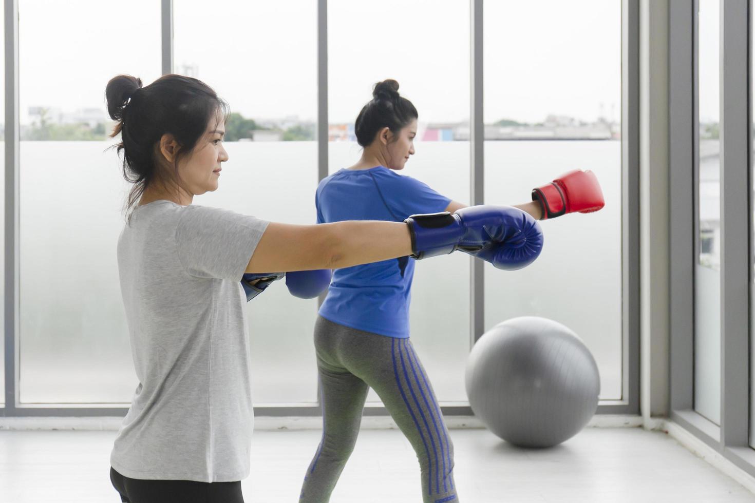 zwei asiatinnen mittleren alters, die boxübungen im fitnessstudio machen. foto