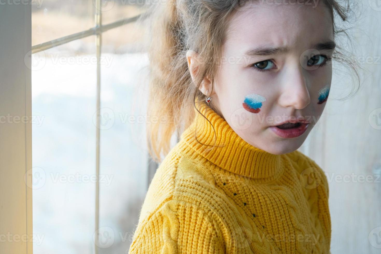 ein trauriges kind am fenster mit der flagge russlands, sorgen sich mit tränen in den augen. Konflikt zwischen Russland und der Ukraine, Angst foto