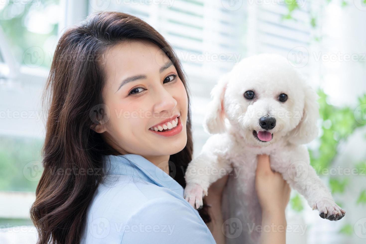 junge asiatische frau, die zu hause mit hund spielt foto