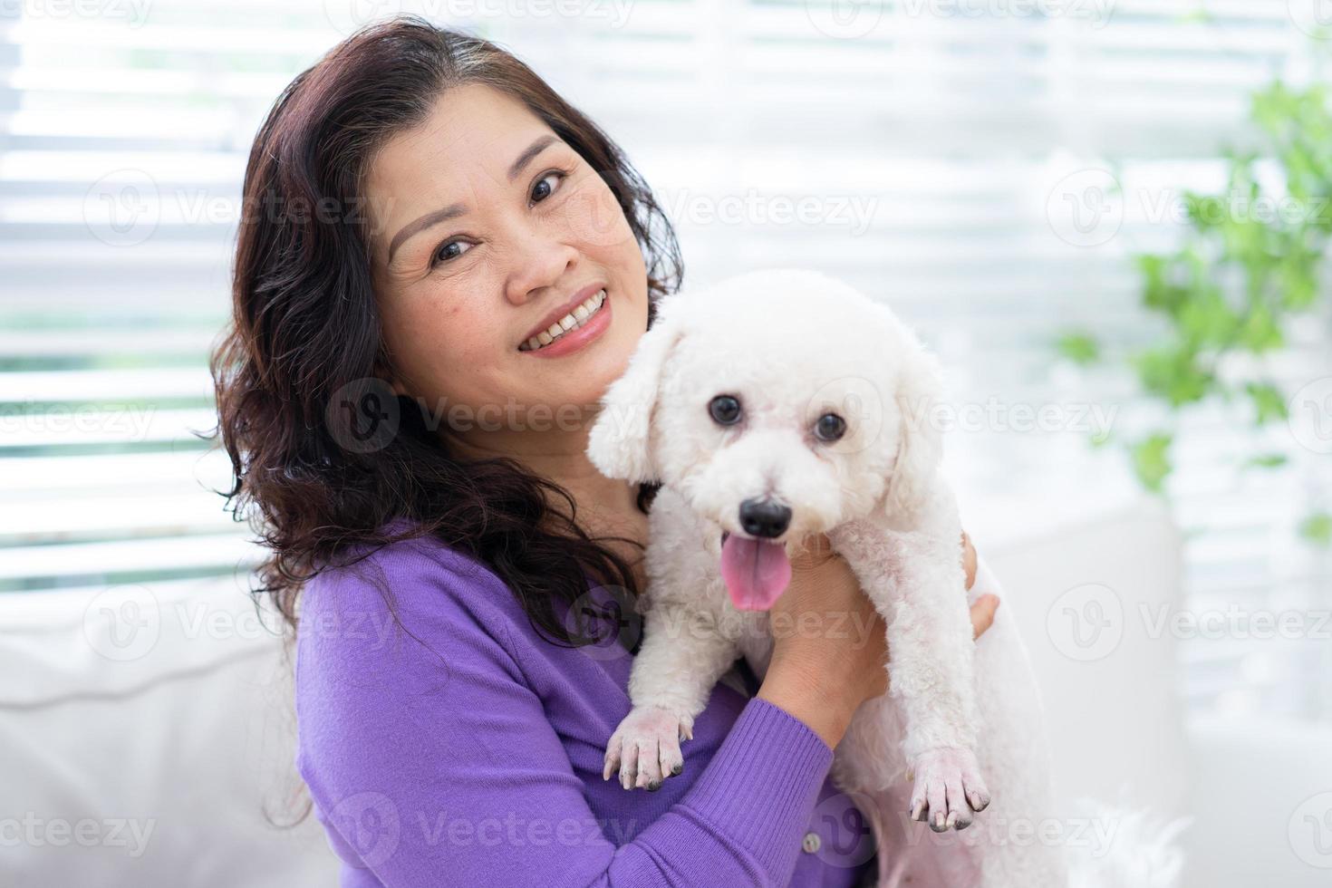 Porträt einer älteren Frau, die ihren Hund umarmt foto