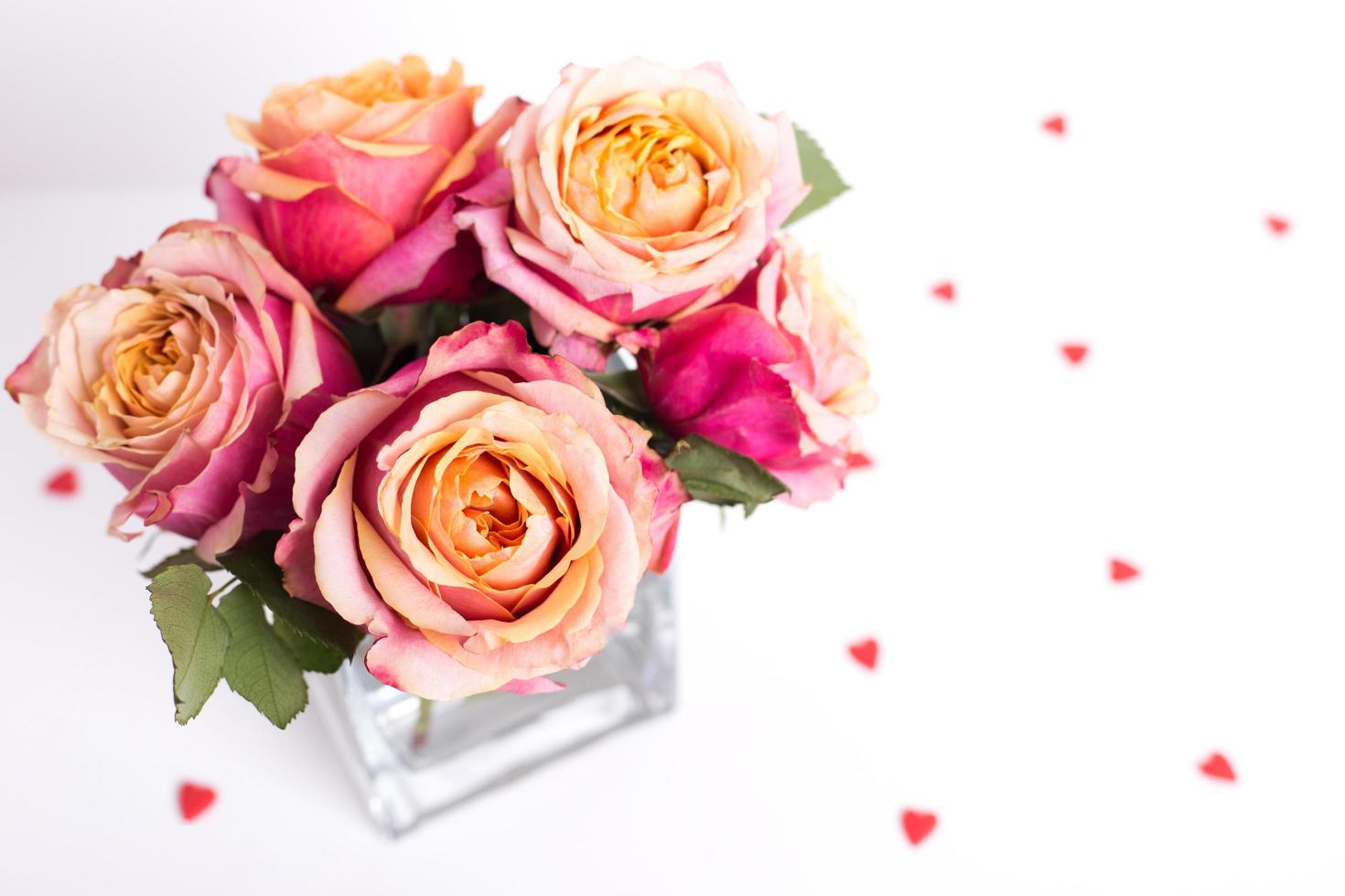 rosafarbene Rosen und Herzformverzierungen auf weißem Hintergrund foto