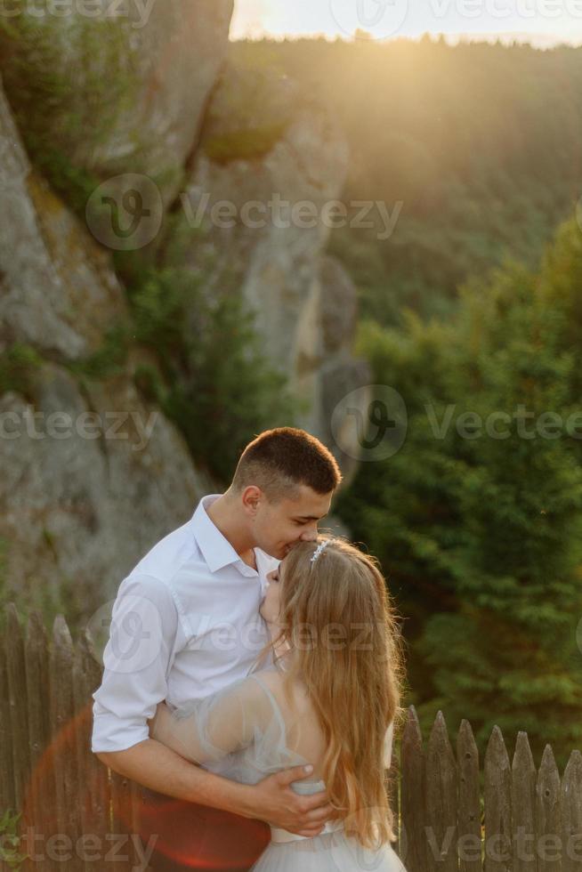 Fotoshooting eines verliebten Paares in den Bergen. Das Mädchen ist wie eine Braut in einem Hochzeitskleid gekleidet. foto