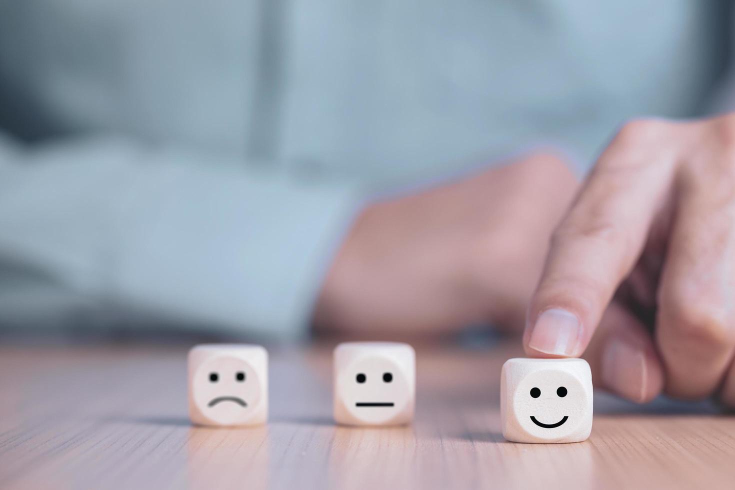 geschäftsmann wählt ein lächeln emoticon symbole stellen ein glückliches symbol auf holzblock, dienstleistungen und kundenzufriedenheitsumfragekonzept dar foto