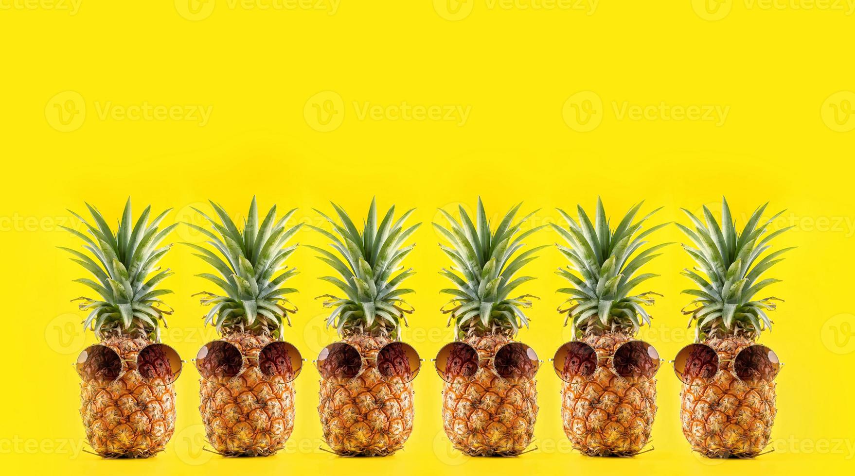 kreative ananas, die mit sonnenbrille und schale isoliert auf gelbem hintergrund nach oben schaut, sommerurlaub strandidee designmuster, kopierraum nah oben foto