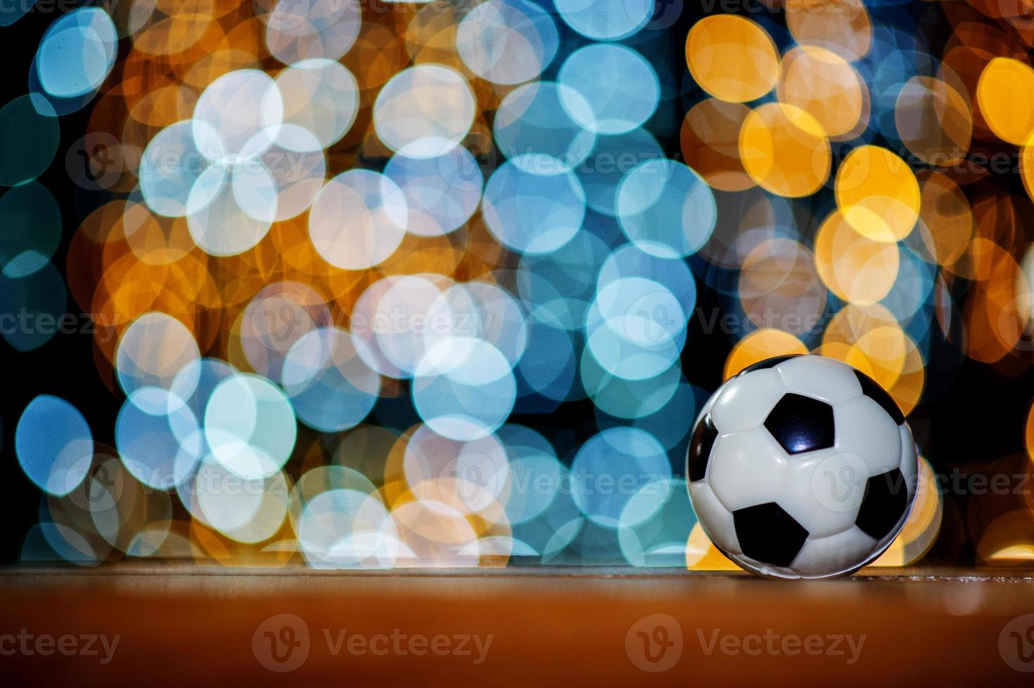 Der weiße Fußballball ist auf einem Stück Holz platziert und hat einen schönen Bokeh-Hintergrund. foto