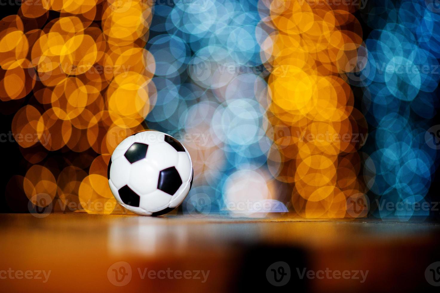 Der weiße Fußballball ist auf einem Stück Holz platziert und hat einen schönen Bokeh-Hintergrund. foto