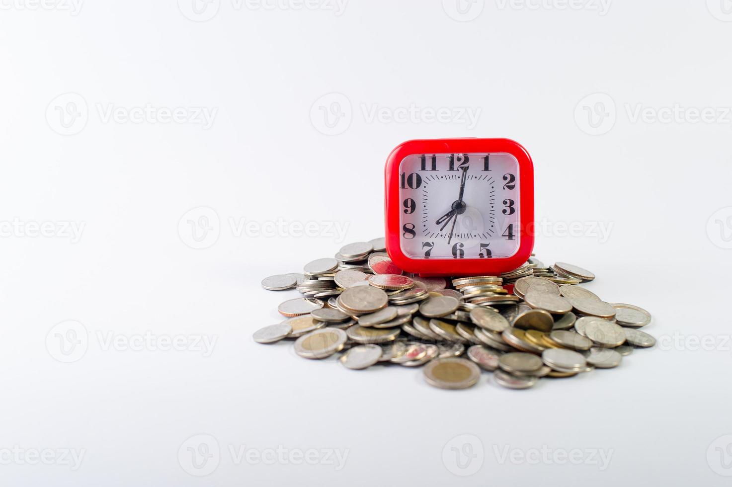 Geld, Baht-Münzen auf weißem Hintergrund und eine rote Uhr foto