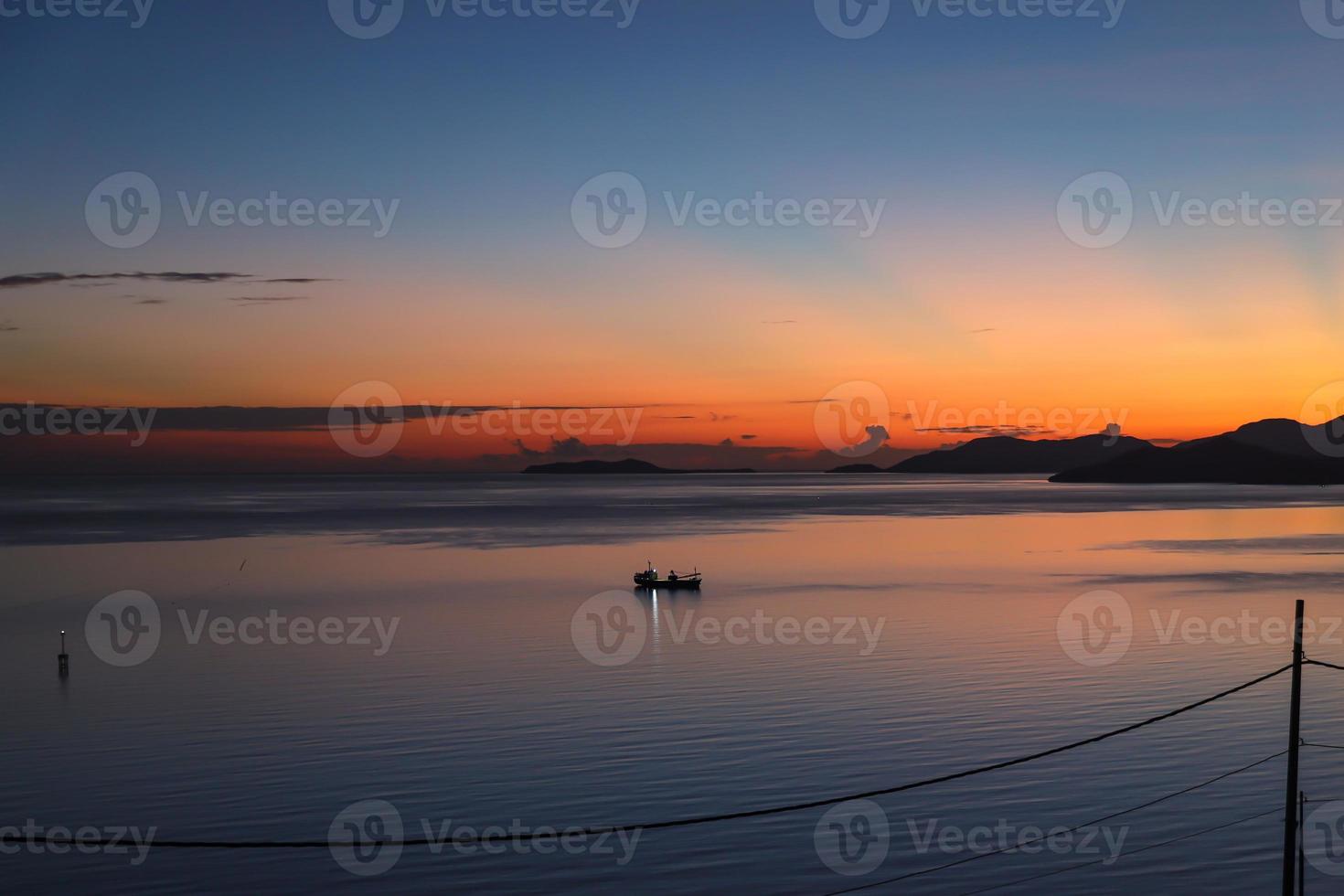 Malerischer Blick von der Silhouette des Fischerbootes in ruhigem Meer bei Sonnenaufgang foto