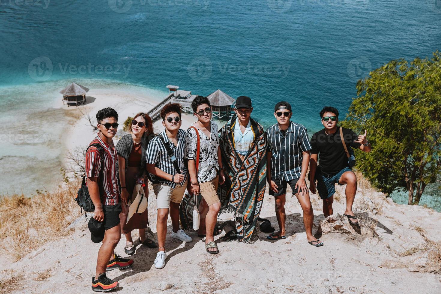 asiatische touristen machen zusammen ein foto auf den hügeln mit dem exotischen strand von labuan bajo