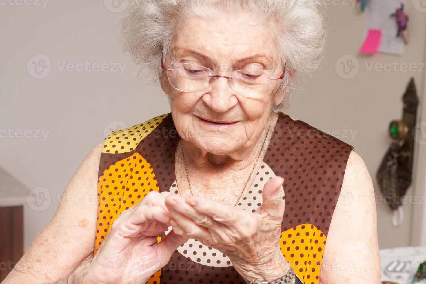 ältere dame zu hause, die ihre trockenen hände inspiziert foto
