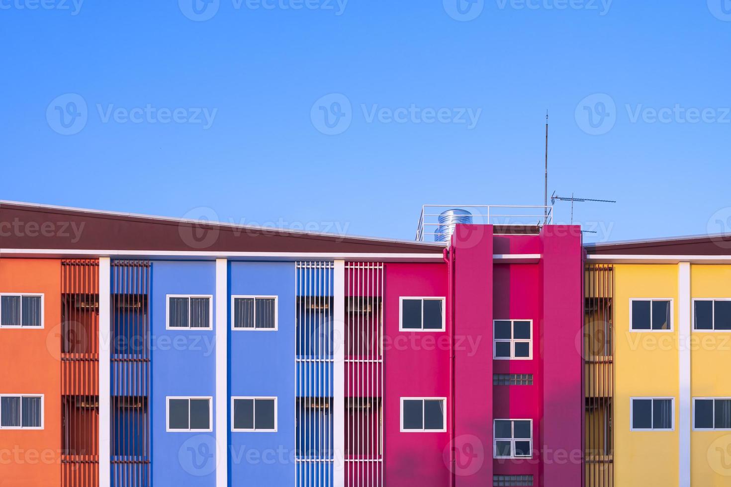 Glasfenster und Sicherheitsbaluster mit Wassertank aus Edelstahl im oberen Teil des farbenfrohen Wohnhauses vor blauem Himmelshintergrund foto