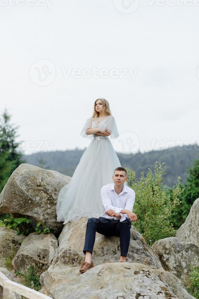 Fotoshooting eines verliebten Paares in den Bergen. Das Mädchen ist wie eine Braut in einem Hochzeitskleid gekleidet. foto