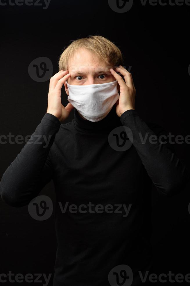 Mann mittleren Alters mit medizinischer Gesichtsmaske Porträt aus nächster Nähe veranschaulicht die pandemische Coronavirus-Krankheit auf dunklem Hintergrund. Covid-19-Ausbruchkontaminationskonzept. foto