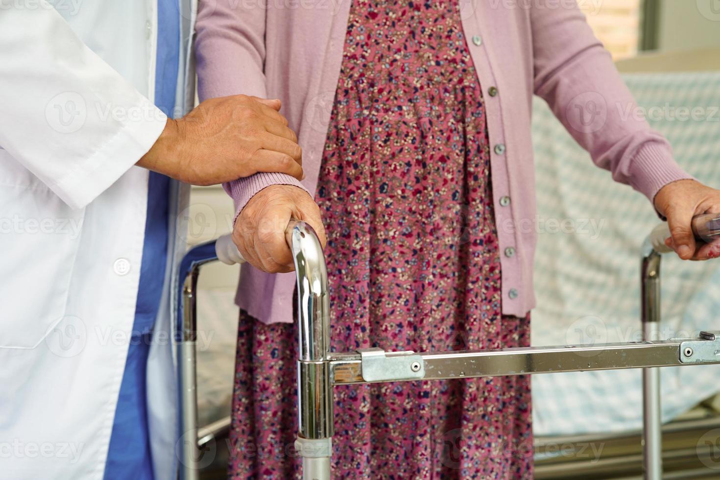 arzt hilft asiatischen älteren frauen mit behinderungspatienten zu fuß mit gehhilfe im pflegekrankenhaus, medizinisches konzept. foto