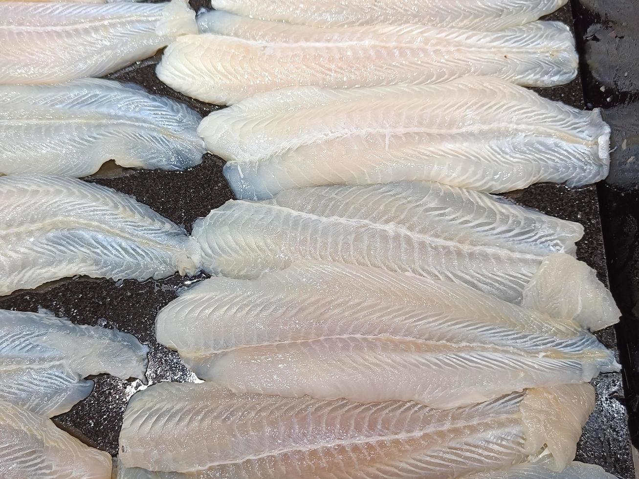frische Fischfilets, geschnitten auf einem schwarzen Tablett foto