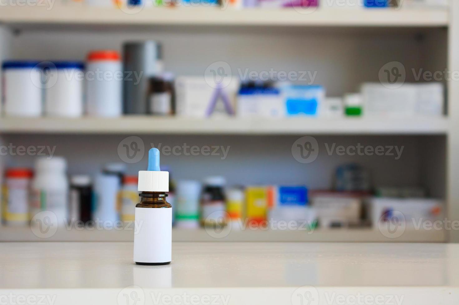 medizinische glasbraune flasche mit weißem etikett, nasentropfenmedizin mit unscharfem hintergrund der drogerieregale foto