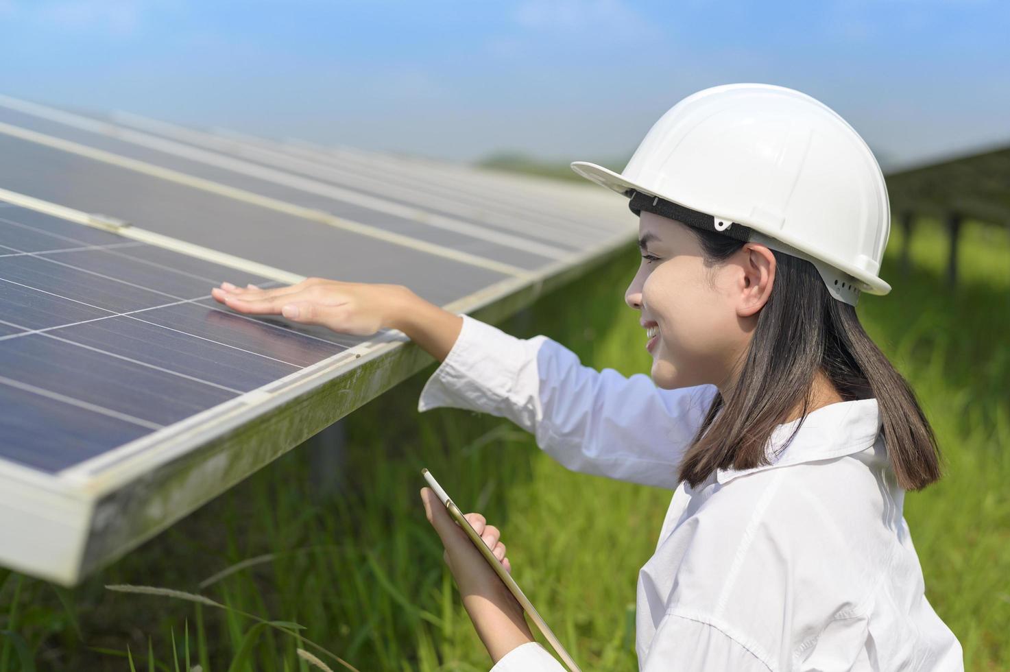 Ingenieurin mit Helm auf dem Feld der Photovoltaikzellen oder Sonnenkollektoren, umweltfreundliche und saubere Energie. foto