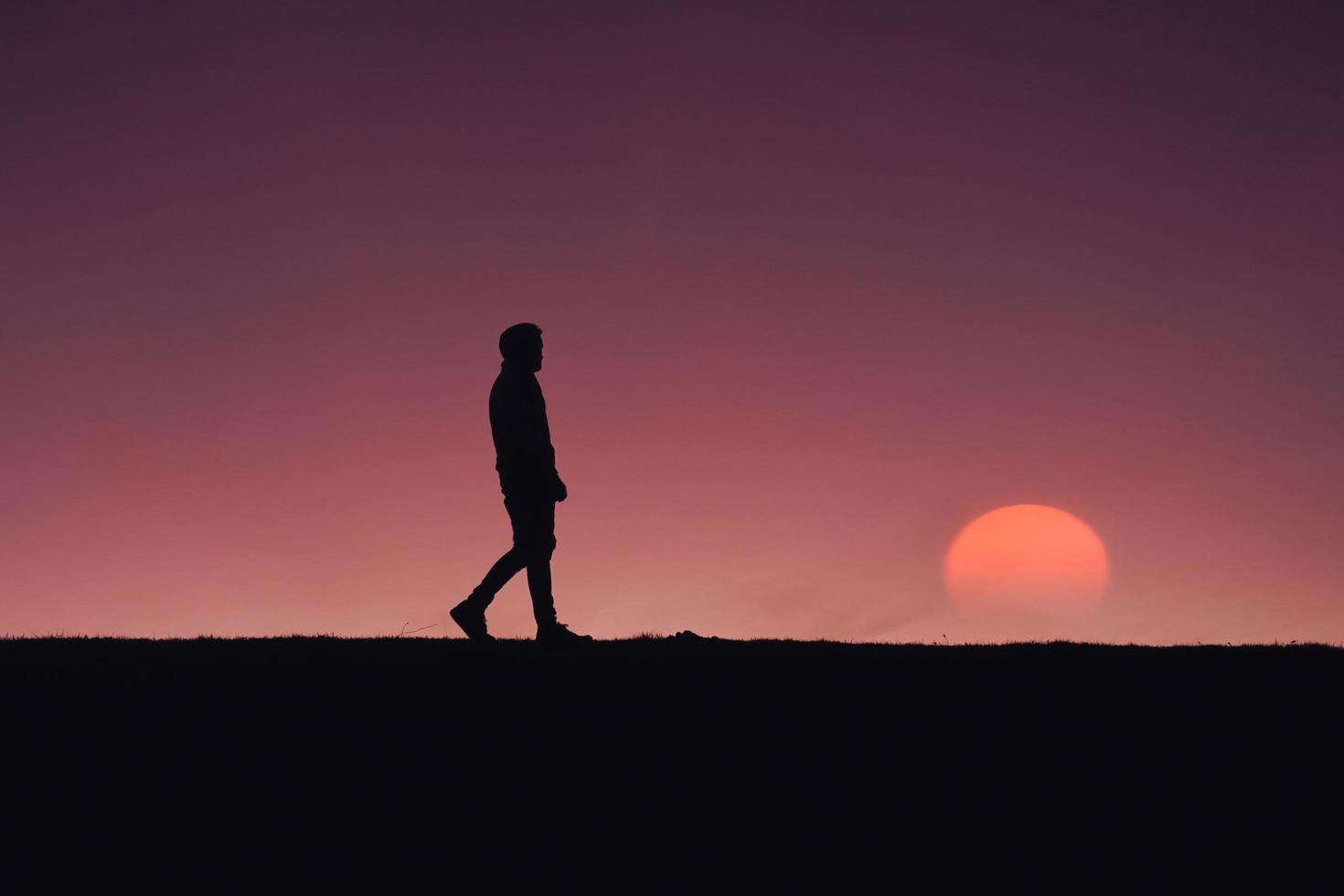 Silhouette eines erwachsenen Mannes im Berg mit einem romantischen Sonnenuntergangshintergrund foto