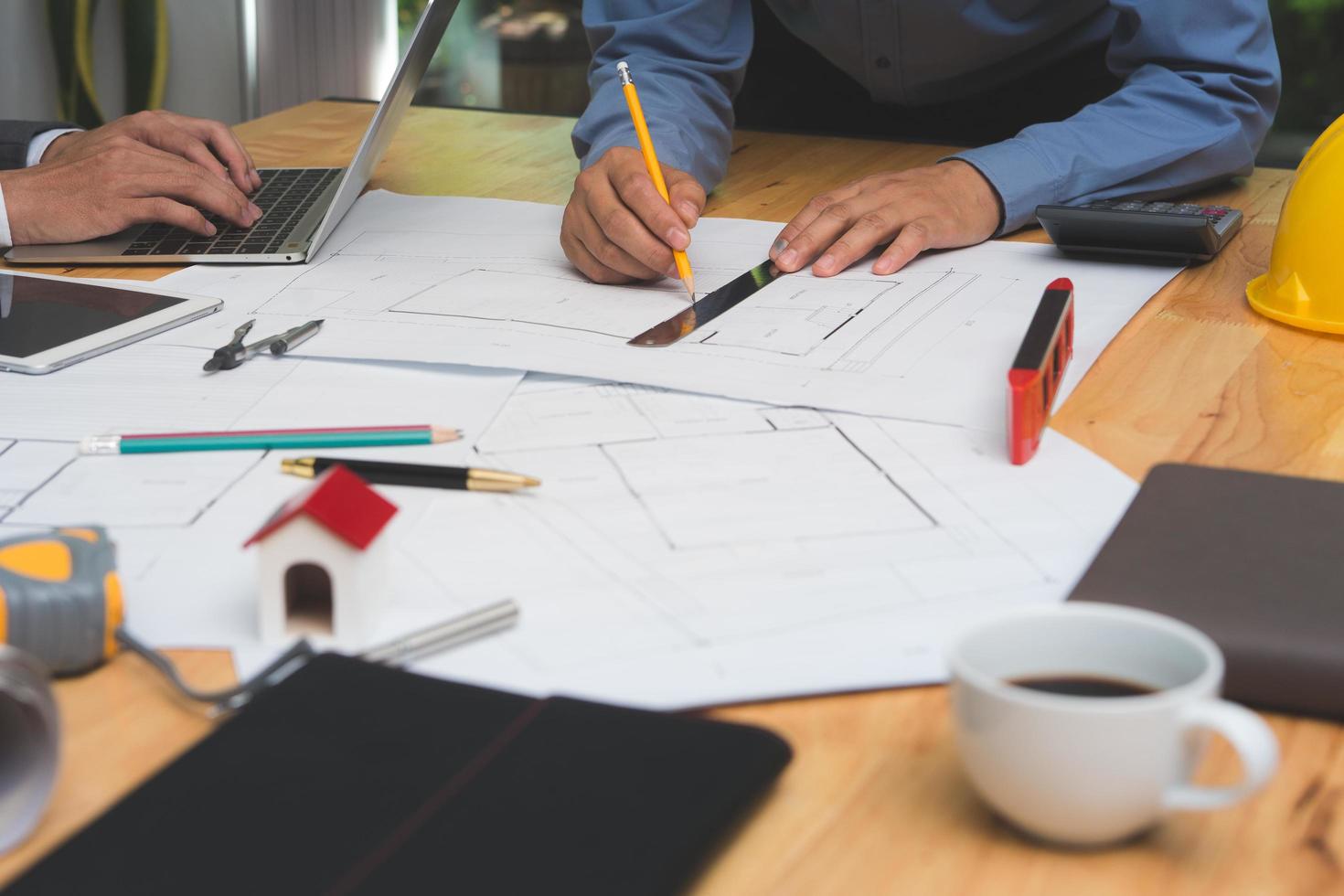 team von architekten oder ingenieuren, die auf dem schreibtisch mit entwurf über ein neues startprojekt auf dem schreibtisch diskutieren. teamgruppe auf der baustelle überprüfen sie dokumente und geschäftsabläufe. selektive fokussierung. foto