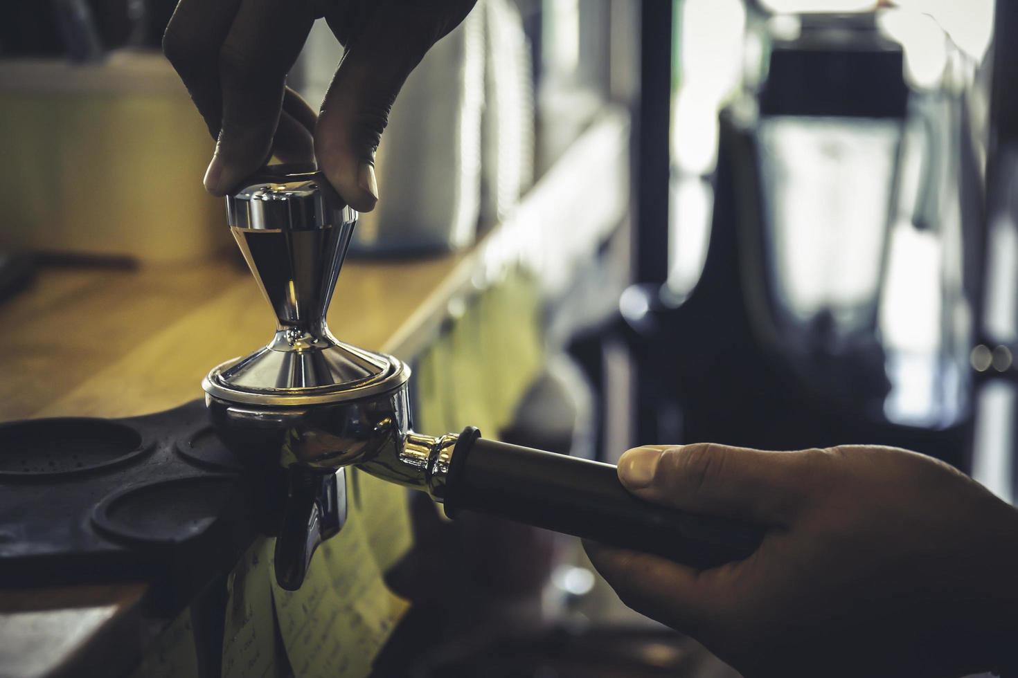 Der Barista drückt mit seiner Hand das Kaffeepulver in den Block, falls der frisch geröstete Kaffee aus der Streaming-Maschine entsaftet wird. foto