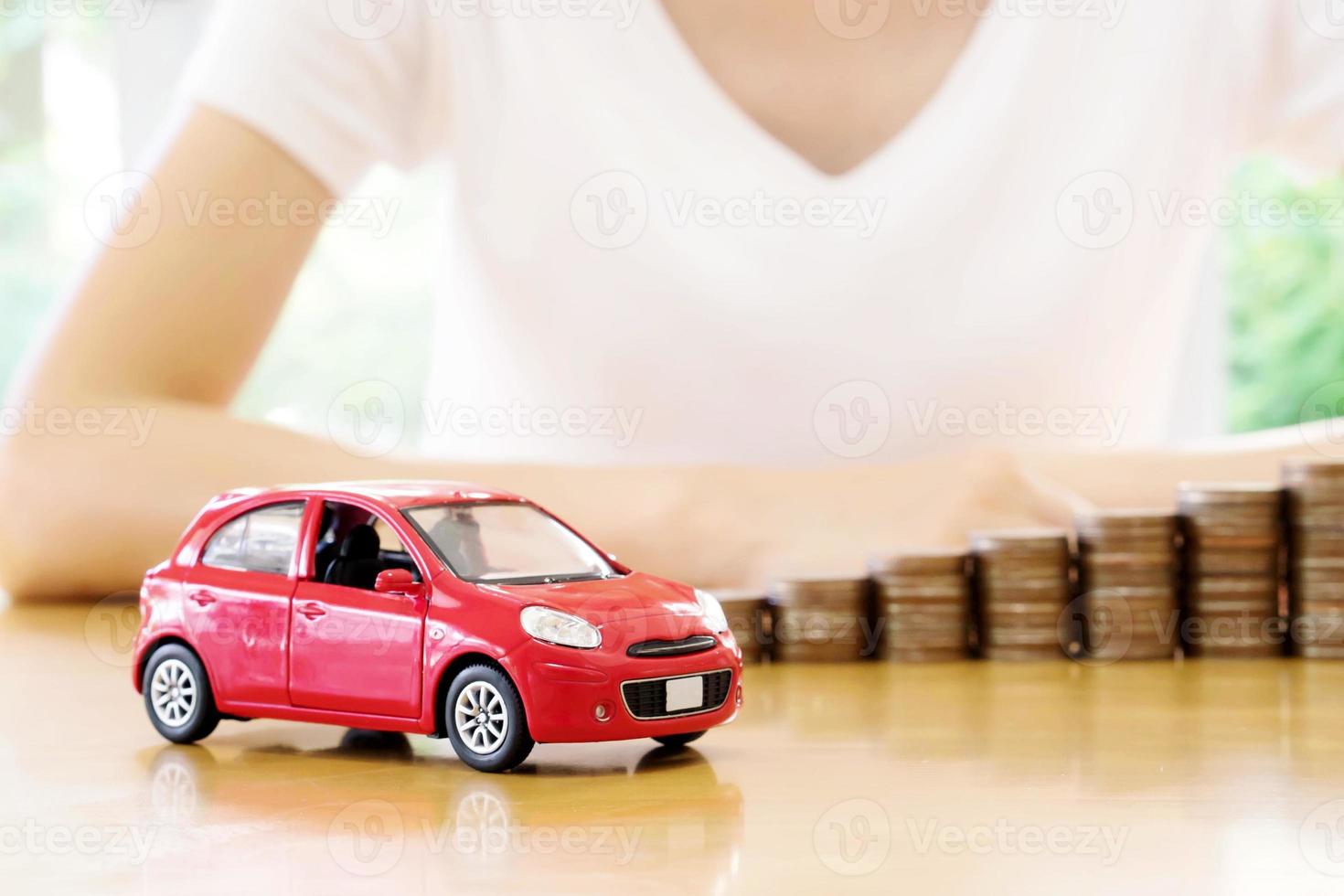 Geschäftsfrau ein Spielzeugauto und ein Stapel Münzen foto