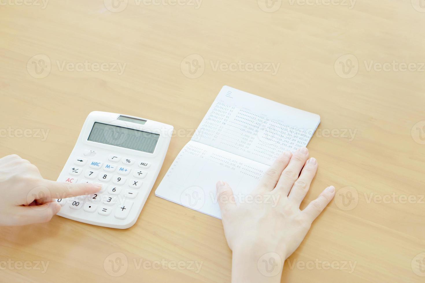 Geschäftsfrau verwendet Taschenrechner neben Sparbuch foto